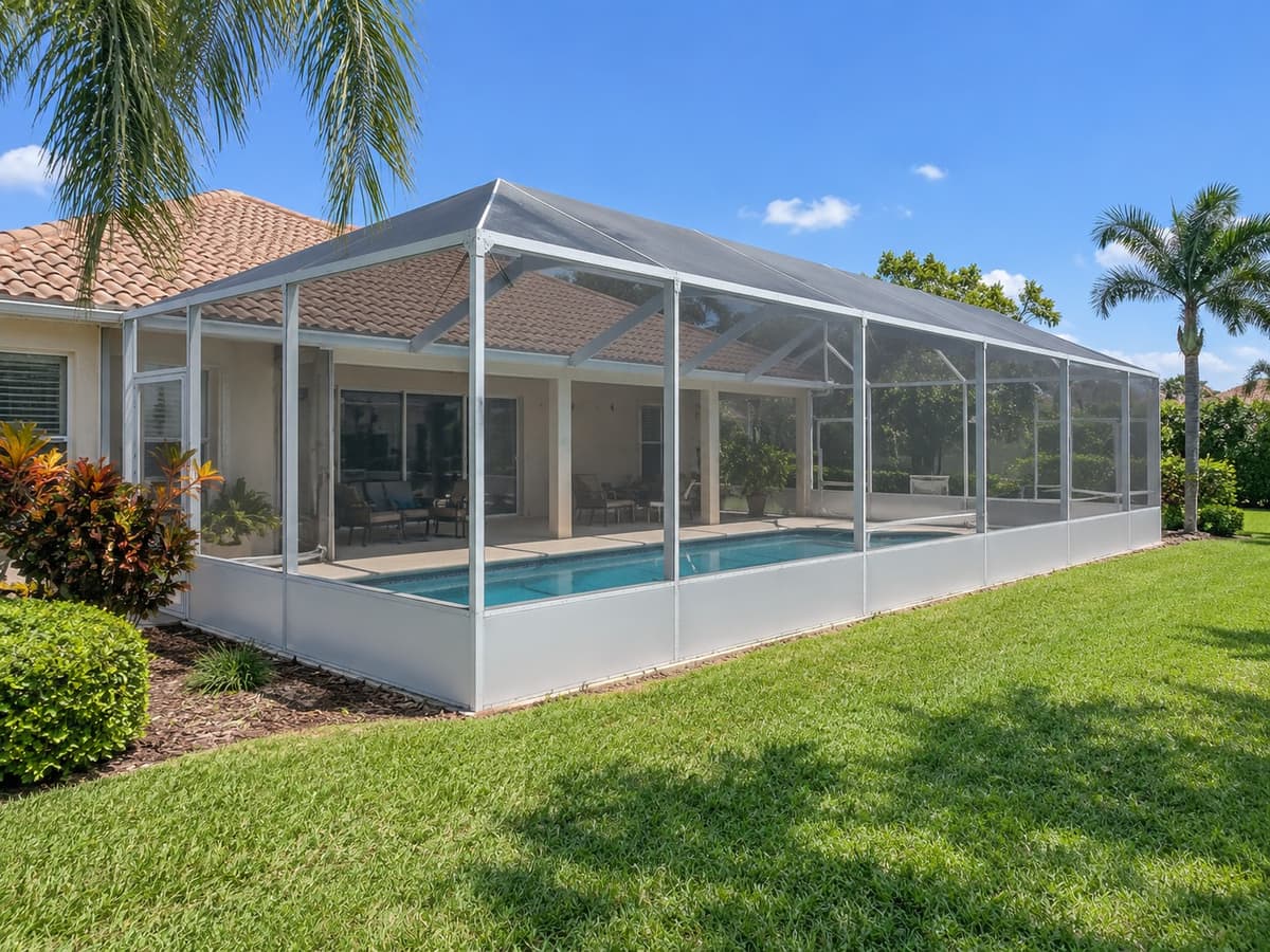 Long pool screen enclosure along the back of a Florida home with a tile roof